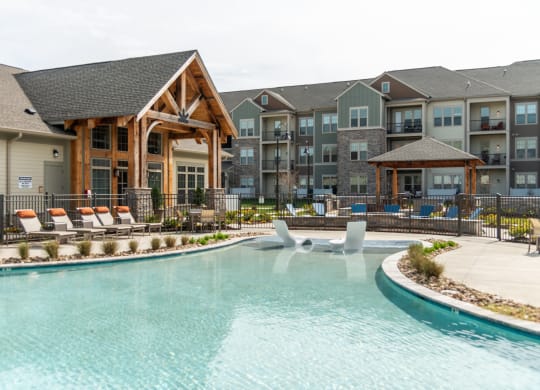 a swimming pool with lounge chairs and a lazy river in front of an apartment building at The Whitworth, Virginia