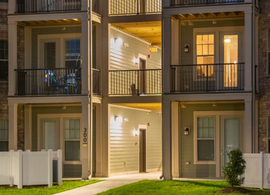 an apartment building at night with a green lawn in front of it at The Whitworth, Williamsburg, VA, 23185