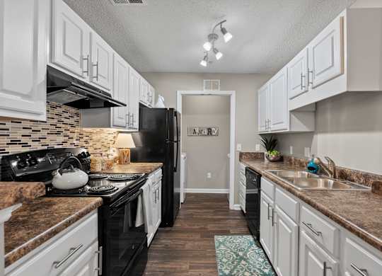 A kitchen with black appliances and white cabinets.