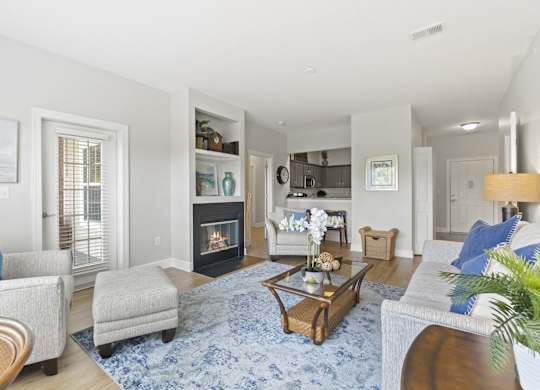 A living room with a fireplace and a blue rug.