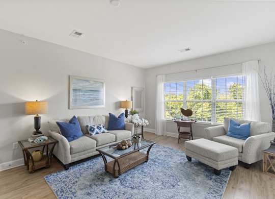 A living room with a grey couch, a blue rug, and a painting on the wall.