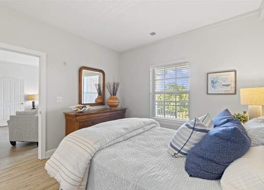A bedroom with a large bed and a mirror on the dresser.