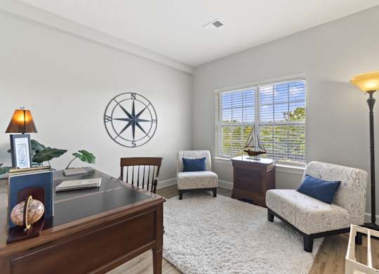 A room with a compass on the wall and a lamp on the desk.