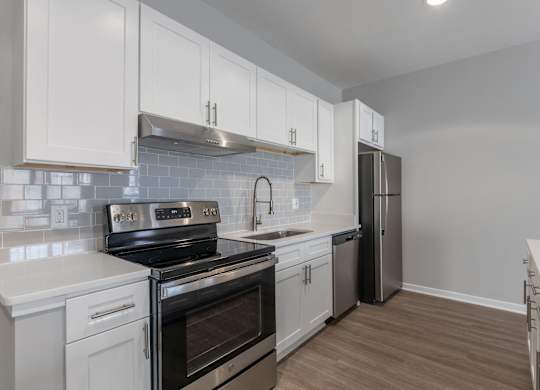 an empty kitchen with white cabinets and stainless steel appliances