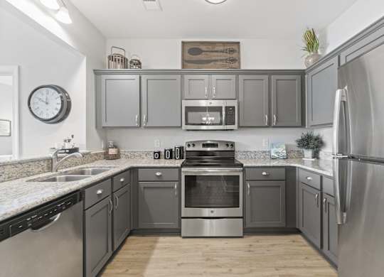 A kitchen with a stainless steel refrigerator and a stove with an oven.