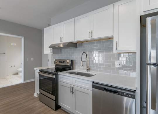 a kitchen with white cabinets and stainless steel appliances and a sink