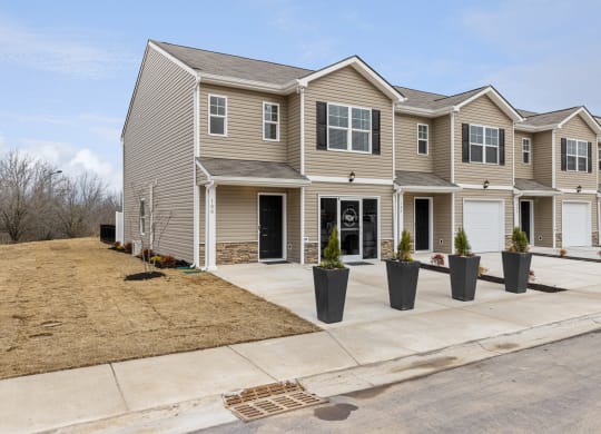 a tan house with potted plants in front of a driveway at Summit Place Apartments, Oak Ridge, Tennessee