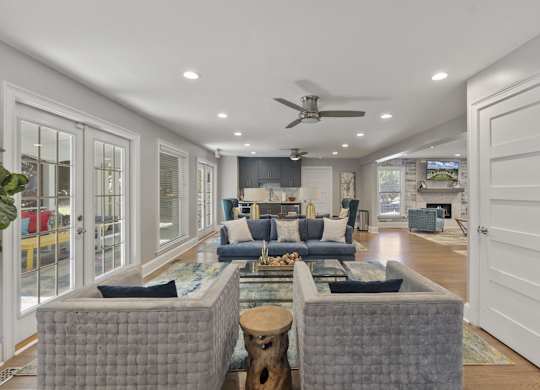 A clubhouse room with a grey sofa set and a ceiling fan.