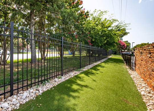 a black wrought iron fence in front of a green lawn and trees at Mayton Transfer Lofts in Petersburg, Virginia