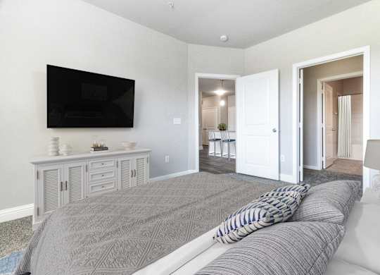 A living room with a grey sofa and a television on the wall.