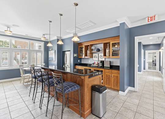 a communal kitchen with a bar and chairs in a lobby
