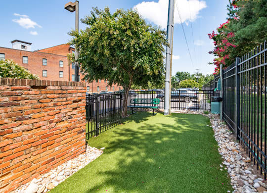 a yard with a bench in front of a black fence at Mayton Transfer Lofts in Virginia 23803