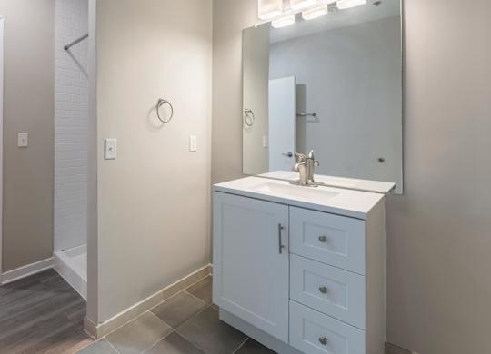 A white bathroom vanity with a mirror and lights above it.