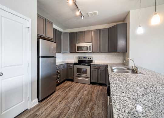 A modern kitchen with dark brown cabinets and stainless steel appliances.