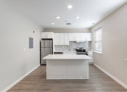 A kitchen with white cabinets and a wooden floor.