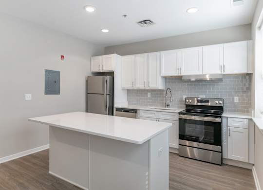 A kitchen with a white island and stainless steel appliances.