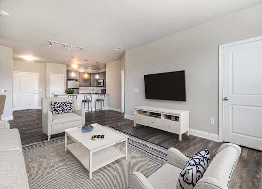 A living room with a white couch, a coffee table, and a television.