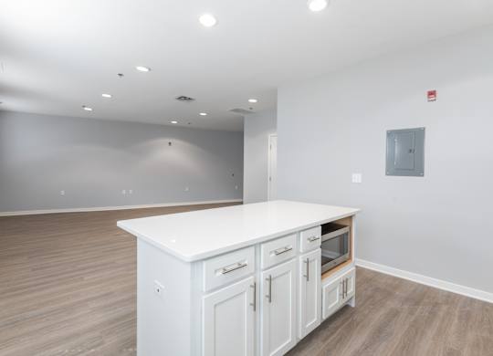 A white kitchen island with wooden cabinets in a room with a grey wall.