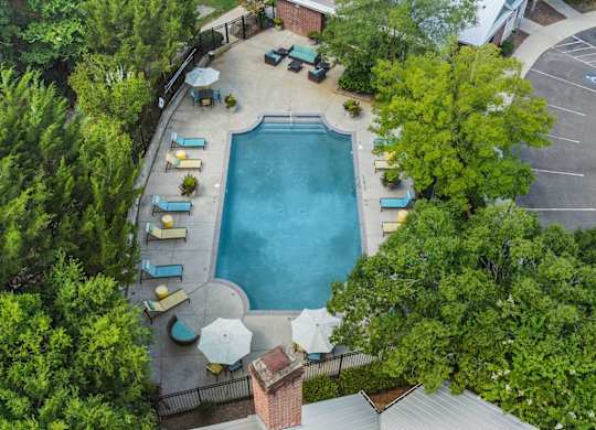 An aerial view of a pool surrounded by trees and chairs.