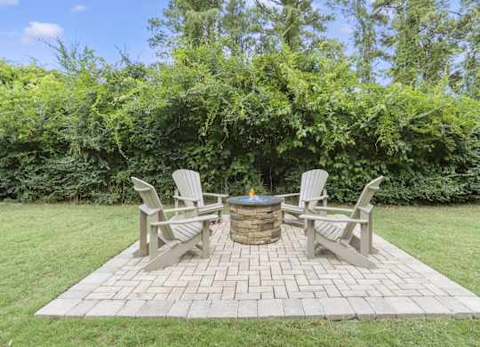 a backyard with a patio with chairs and a fire pit