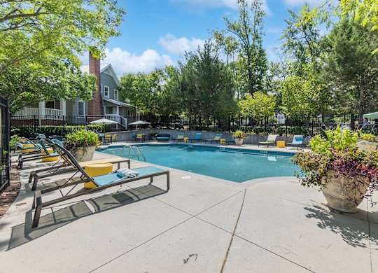 A pool surrounded by trees and chairs.