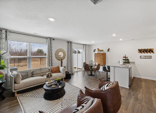 a living room with couches and chairs and a kitchen with a large window at Summit Place Apartments, Oak Ridge, TN