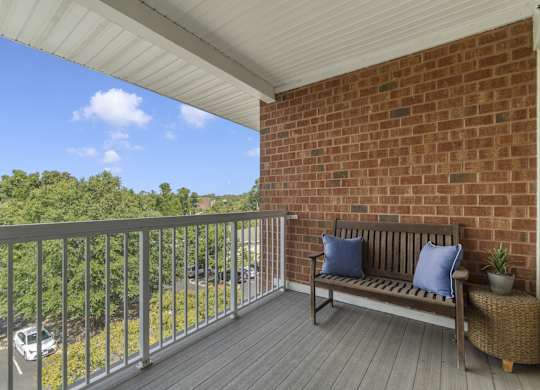 a porch with a bench and a brick wall