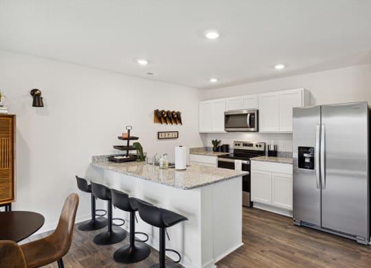 a kitchen with stainless steel appliances and a counter top with bar stools at Summit Place Apartments, Oak Ridge, TN, 37830