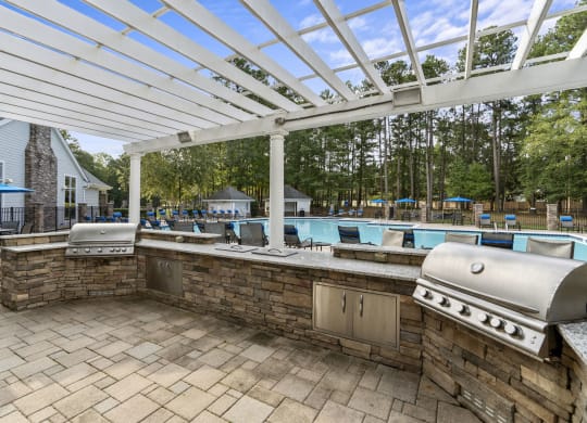 a covered outdoor kitchen with a pool in the background at Trails at Short Pump Apartments, Richmond, VA