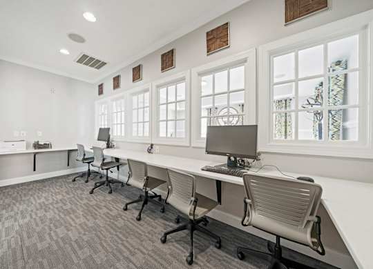 A room with a long desk and chairs with a computer on it.