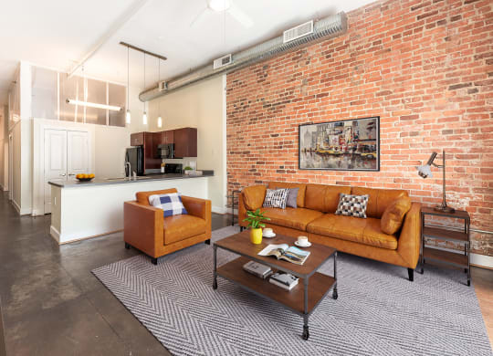 a living room with a brick wall and a couch at Mayton Transfer Lofts in VA 23803