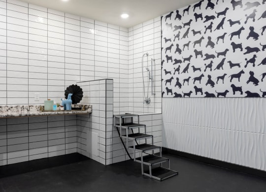a bathroom with white tiles and a black and white pattern on the wall at Tapestry West, VA 23230