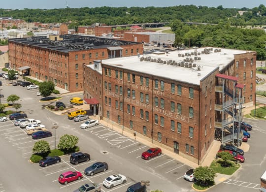 an aerial view of a brick building with cars parked in a parking lot at Mayton Transfer Lofts in Petersburg, VA 23803