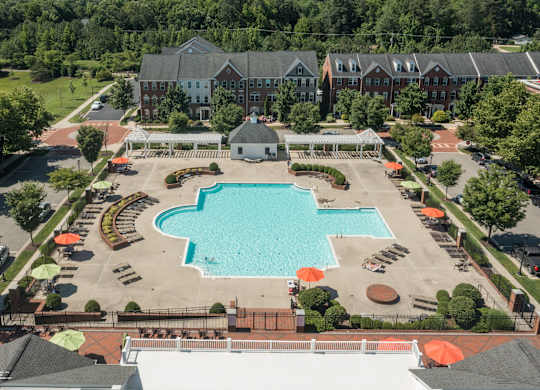 an aerial view of a swimming pool in front of a hotel with trees