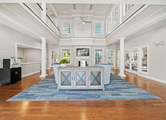 A spacious white hallway with a blue rug and a black cabinet.