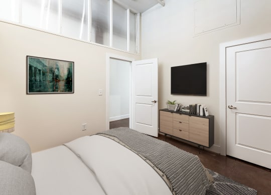 a bedroom with a bed and a tv on the wall at Mayton Transfer Lofts in Petersburg, VA 23803