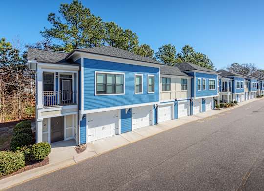 A blue and white mobile home with a porch and a garage door.