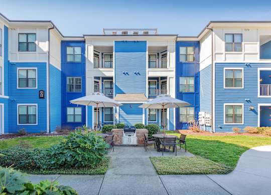 A blue and white apartment building with a patio and umbrellas.