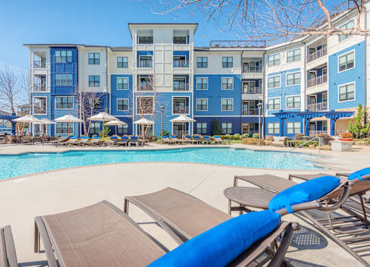 A pool with sun loungers and a building in the background.