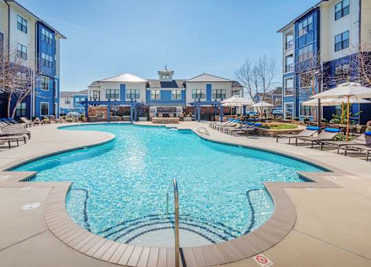 A large swimming pool surrounded by a building and trees.