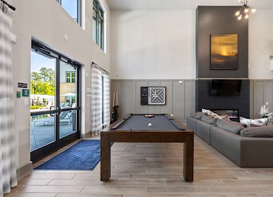 A pool table is in the middle of a room with a couch and a fireplace.