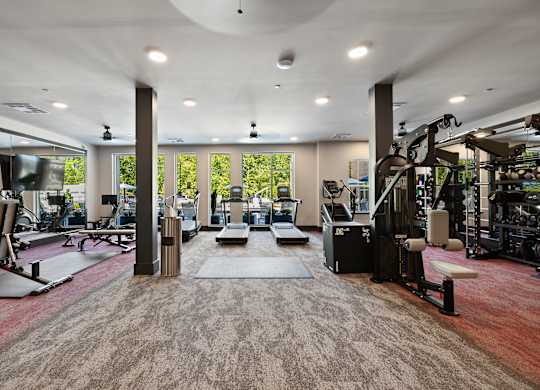 A gym with a variety of equipment and a large window.