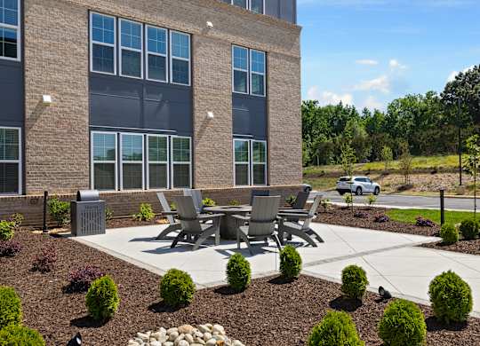 A modern building with a patio and chairs in front.