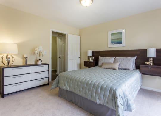 a bedroom with a bed and dressers and a closet at Abbington Place Apartments, Greensboro , North Carolina