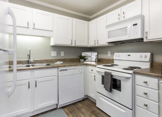 a kitchen with white appliances and white cabinets at Abbington Place Apartments, Greensboro