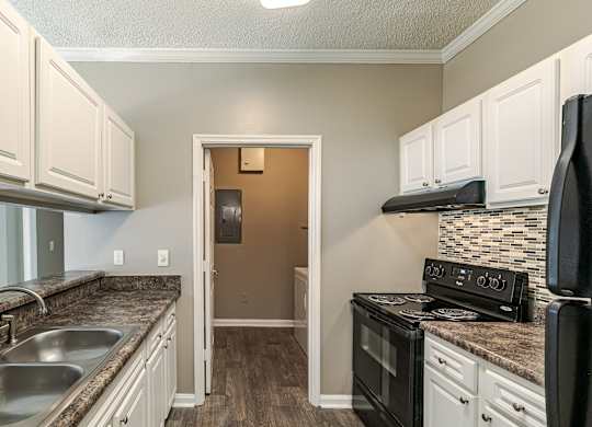 A kitchen with a black stove top oven and white cabinets.