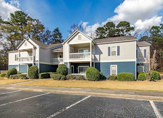 A large two-story apartment building with a parking lot in front.