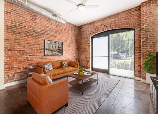 a living room with a couch and a coffee table in front of a brick wall at Mayton Transfer Lofts in Petersburg, Virginia