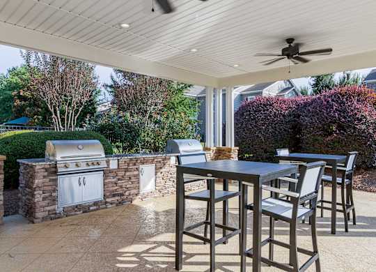 A patio with a table and chairs and a grill.
