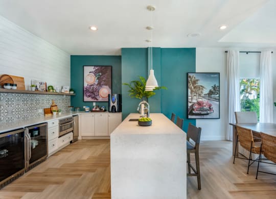 the kitchen and dining area of a house with blue walls and a large white island at The Villas at Ibis Landing, Parkland, FL